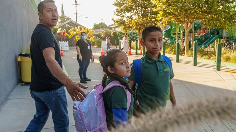 Roberto Garcia drops his children, Lily, 7, center, and Jack,...