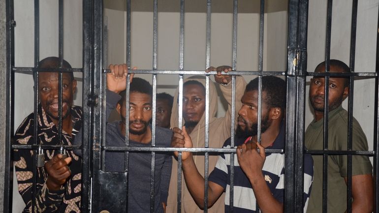 Protesters stand in a cell after a court hearing in...