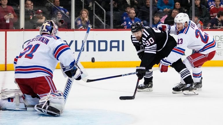 New York Rangers' Adam Fox breaks up a shot by New...