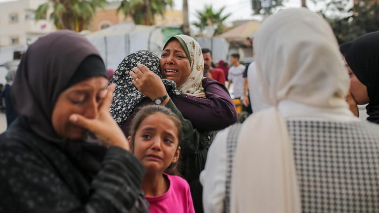 Palestinian women mourn near the bodies of relatives killed in...