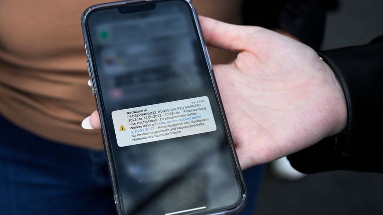 A women shows her cell phone with a warning message...