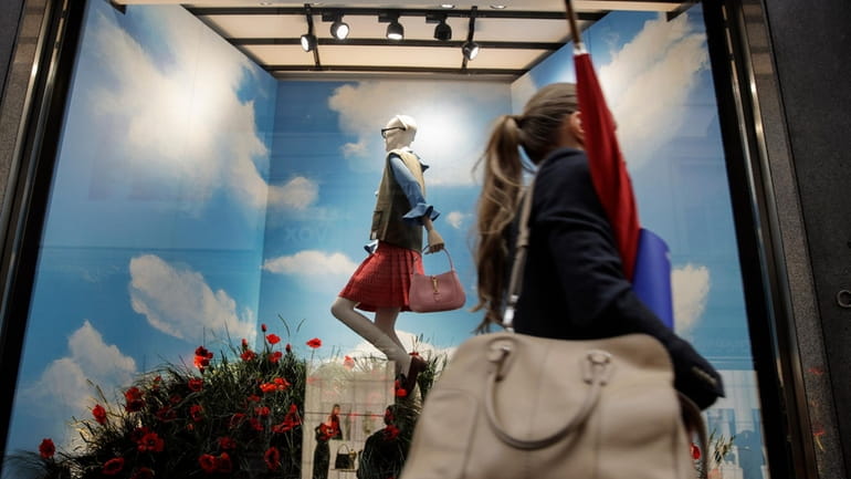 A woman walks past the Gucci store window at the...