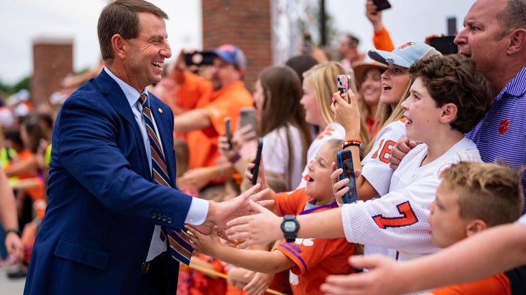 Clemson head coach Dabo Swinney, left, greets fans before an...