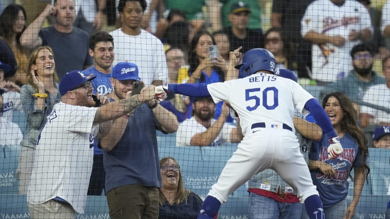 Los Angeles Dodgers' Mookie Betts fist bumps a fan after...