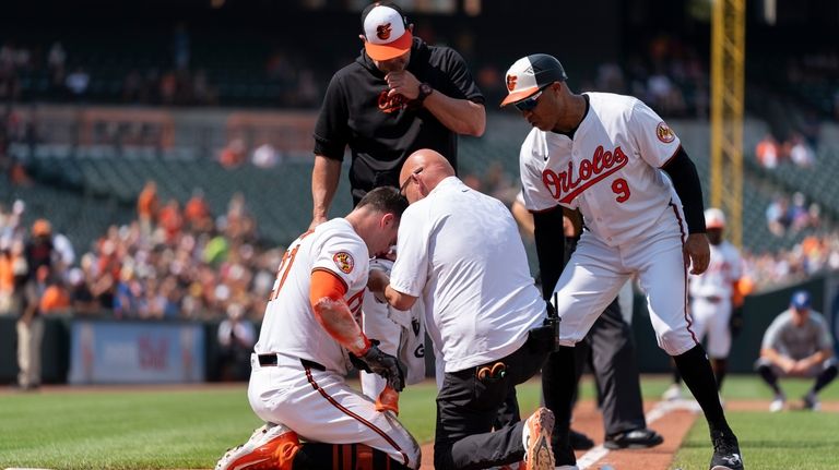 A trainer and coaches attend to Baltimore Orioles' James McCann...