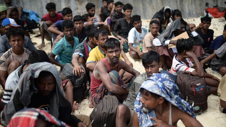 Ethnic Rohingya men sit on a beach after they landed...