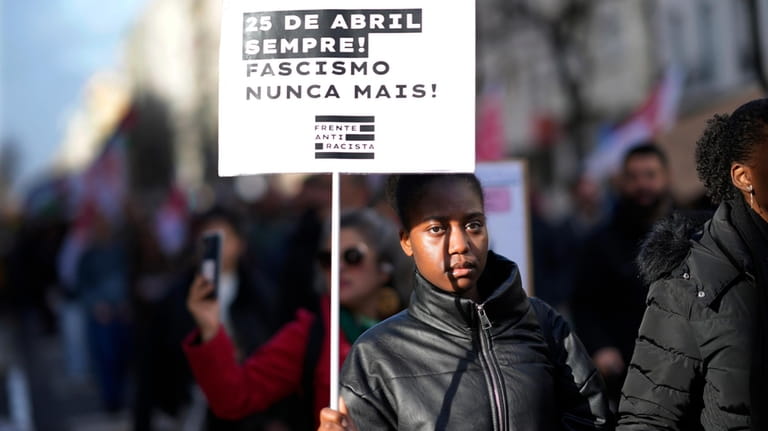 A girl carries a poster with the words "April 25...