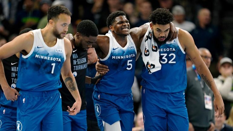 Minnesota Timberwolves guard Anthony Edwards (5) is helped off the...