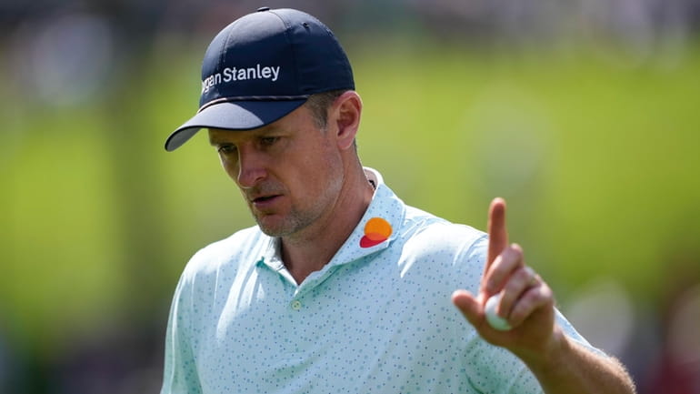 Justin Rose, of England, waves after making a putt on...