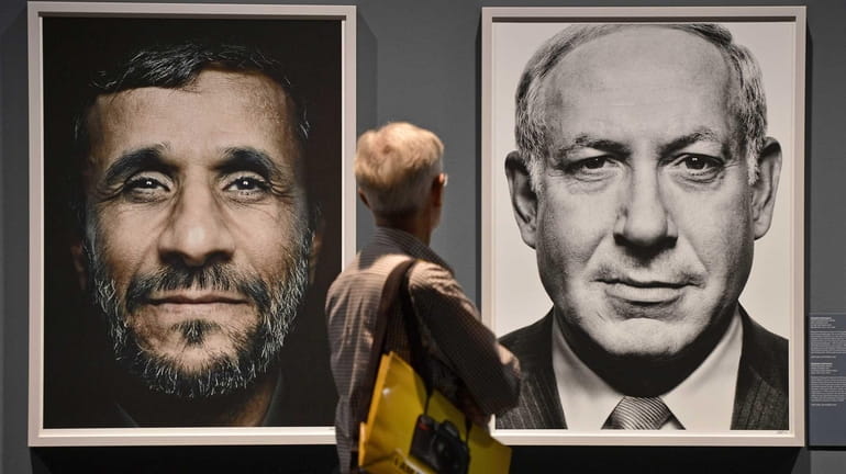 A visitor looks at portraits of Iran's President Mahmoud Ahmadinejad,...