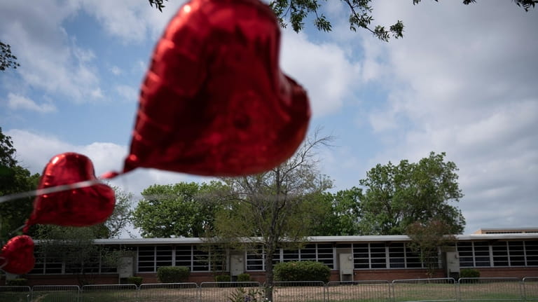 A heart-shaped balloon flies decorating a memorial site outside Robb...