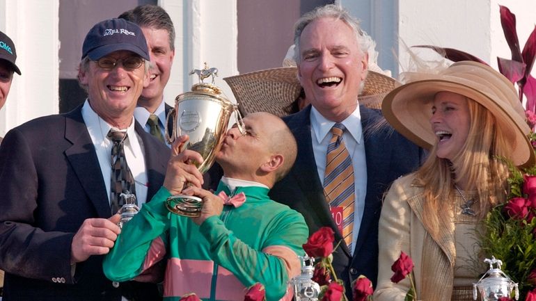 Jockey Mike Smith kisses the trophy as trainer John Shirreffs,...