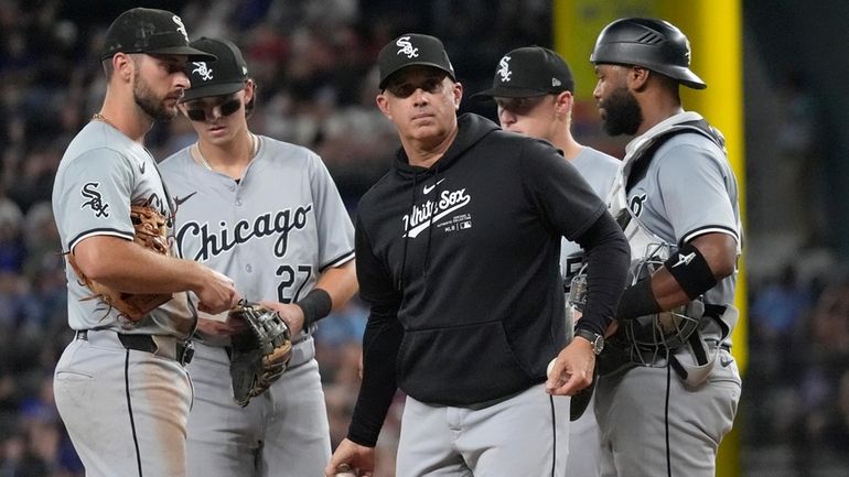 Chicago White Sox manager Pedro Grifol, center, tosses a ball...