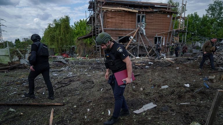 Ukrainian police officers look for fragments of a glide bomb...