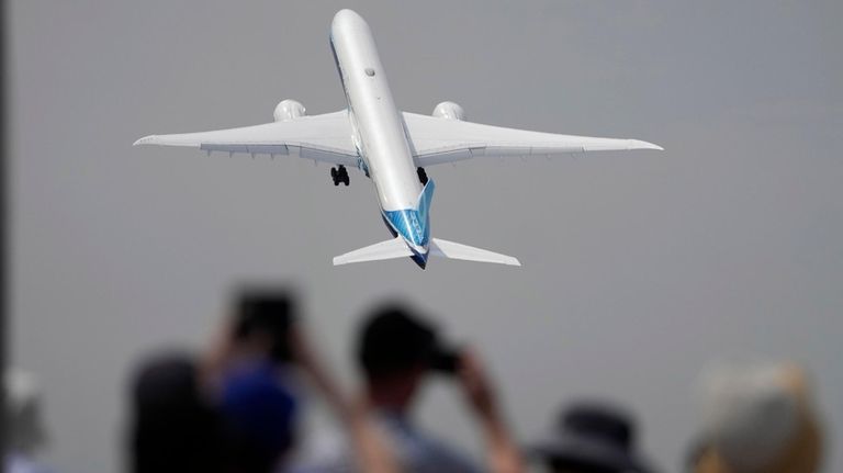 A Boeing 777X plane takes off at the Farnborough Air...