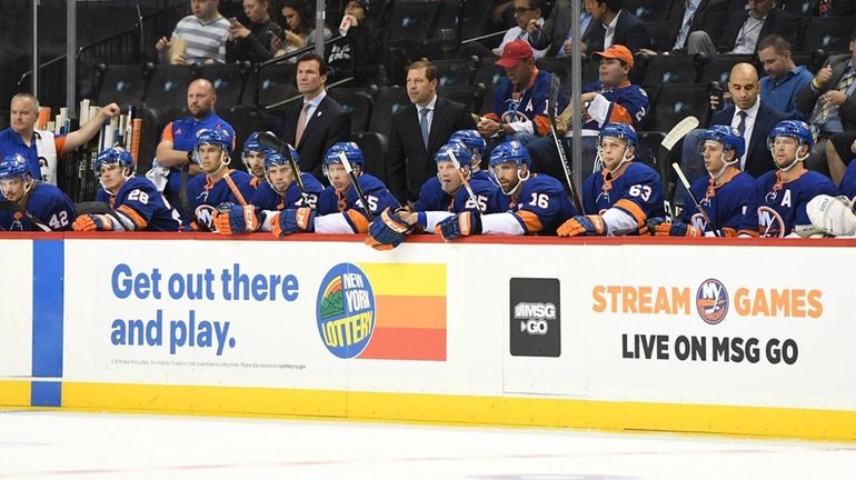 Islanders head coach Doug Weight, center, and players look on...