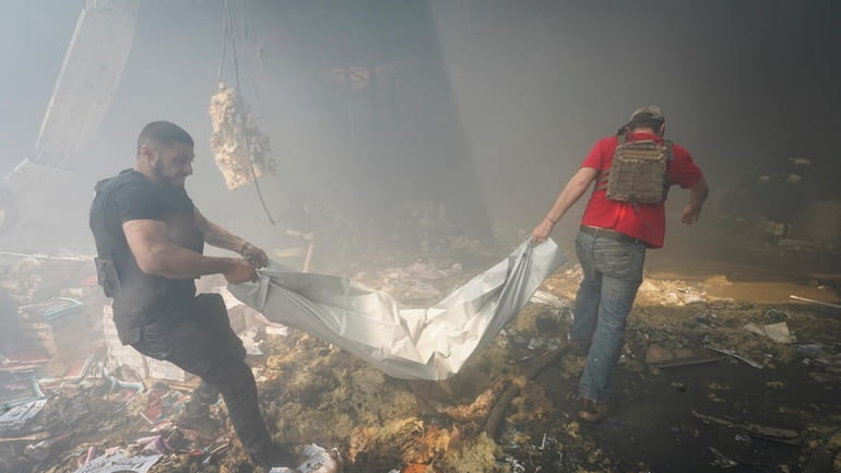 Rescuers carry a body after a Russian missile hit a...