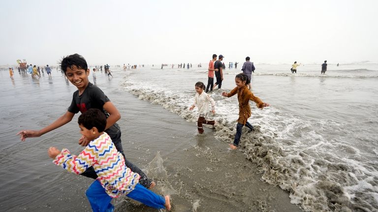 Children enjoy high tide waves on the Clifton beach, during...