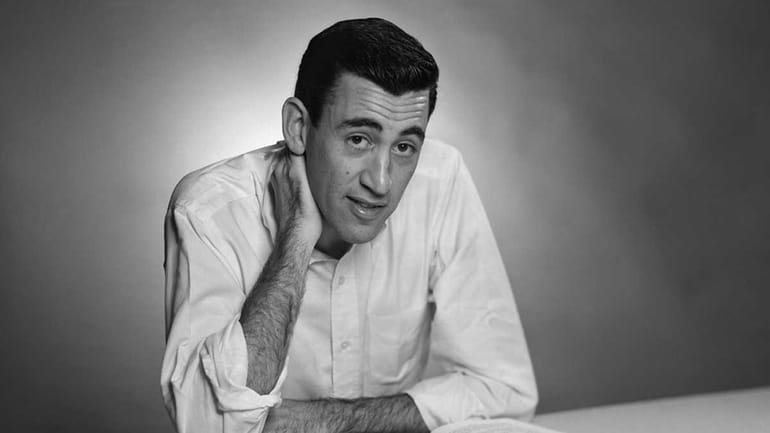 Author JD Salinger poses for a portrait as he reads...