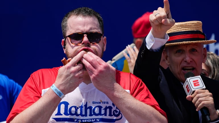 Patrick Bertoletti stuffs hot dogs into his mouth during the...