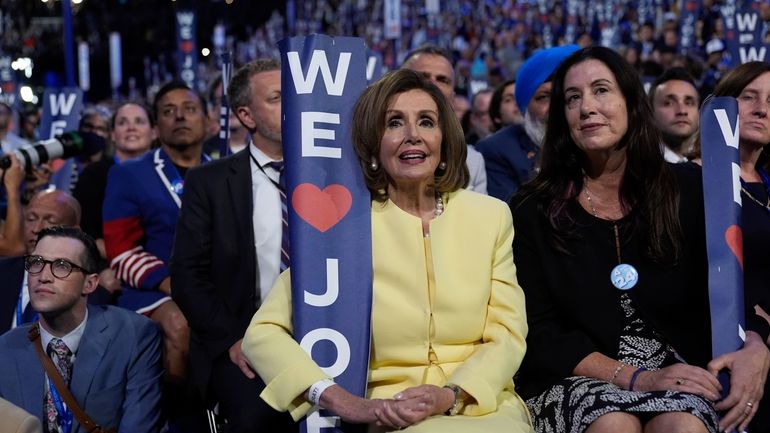 Rep. Nancy Pelosi, D-Calif., holds a sign as President Joe...