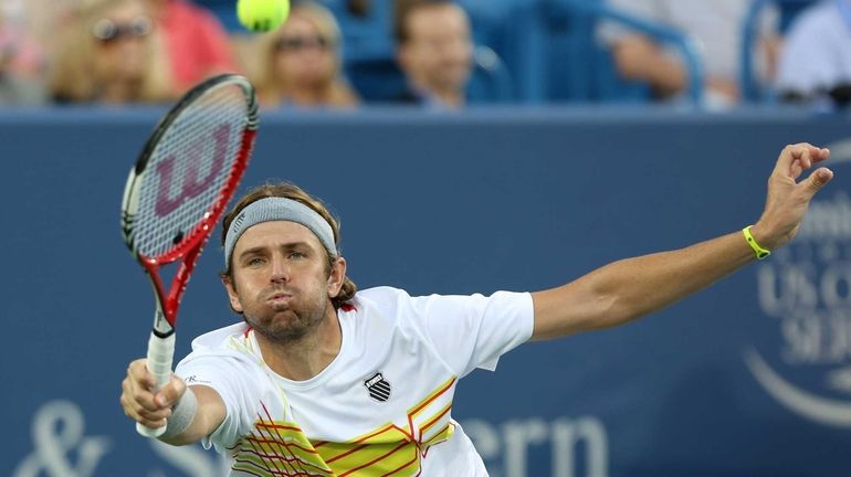 Mardy Fish hits a forehand against Roger Federer of Switzerland...