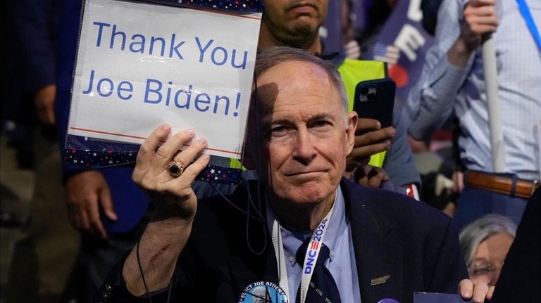 A delegate holds a sign as President Joe Biden speaks...