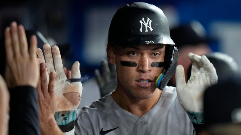 The Yankees' Aaron Judge celebrates with teammates in the dugout...