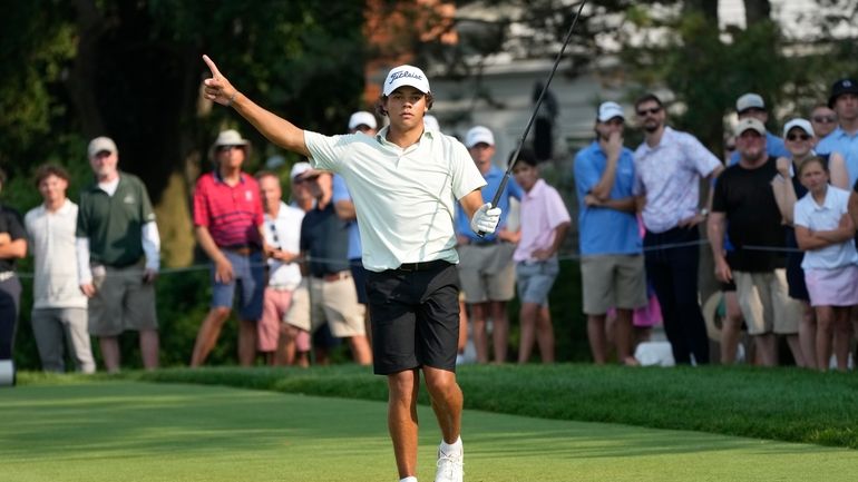 Charlie Woods signals after hitting off the 18th tee during...