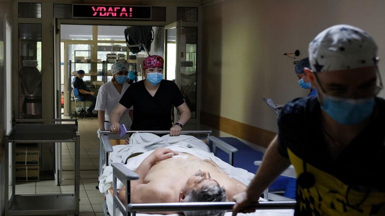 Medical workers transport a Ukrainian serviceman on the stretcher before...