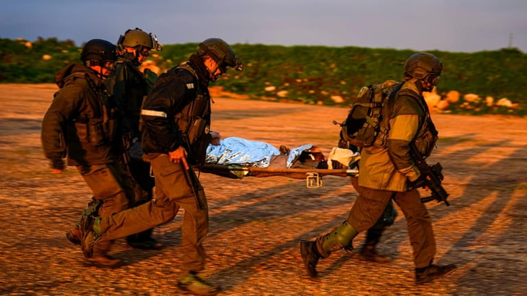 Israeli soldiers run as they carry a stretcher towards a...
