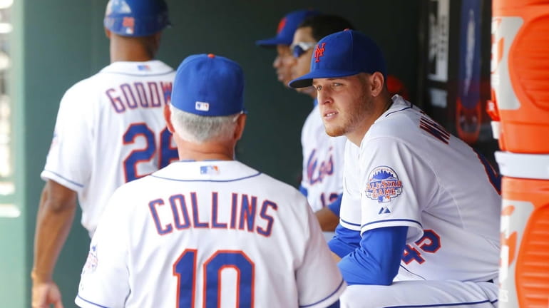 Mets pitcher Zack Wheeler, right, sits in the dugout after...