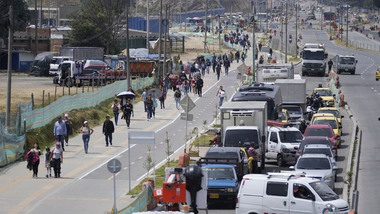 Commuters walk along an avenue blocked by truckers protesting a...