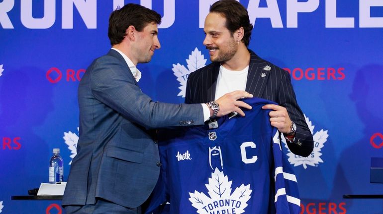 Former Toronto Maple Leafs captain John Tavares, left, hands the...