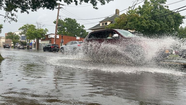 Vehicles navigate through flooding on Main Street, west of Griffing...