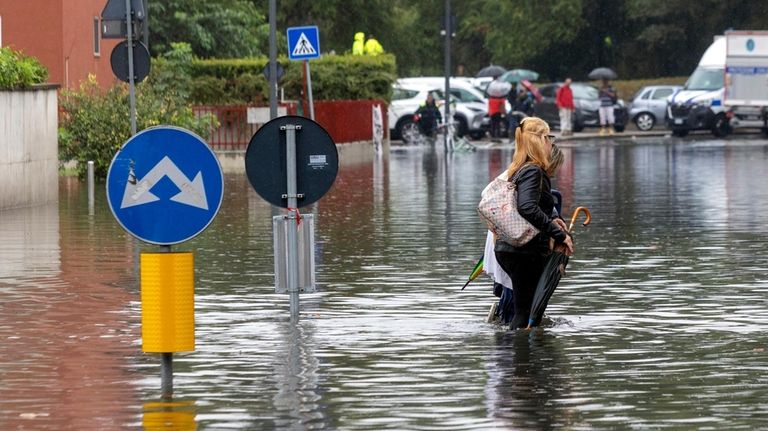 Two women wade through floodwater caused by heavy rain in...