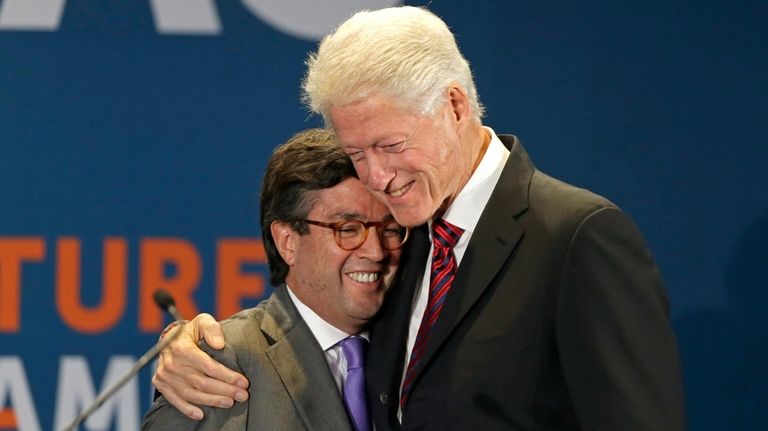 Former President Bill Clinton hugs Luis Alberto Moreno, left, President...