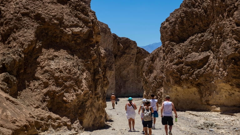 Hikers turn back to their vehicles in Golden Canyon on...