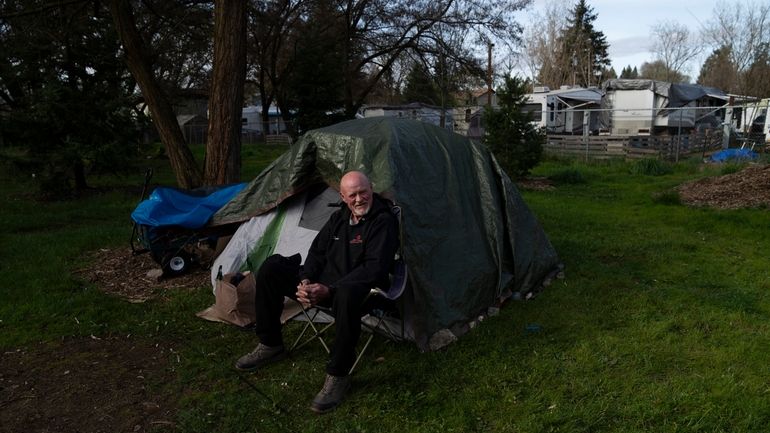 David Wilson sits outside his tent at Riverside Park on...