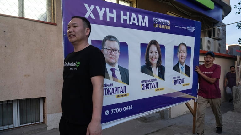 Workers remove publicity poster two days before polls open in...