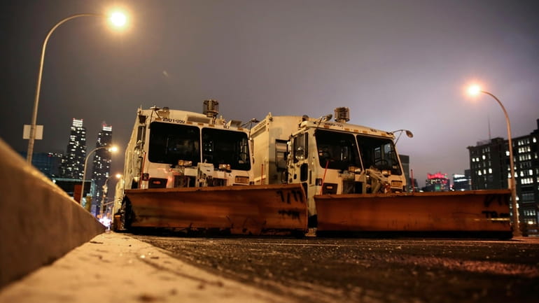 FILE — Sanitation trucks mounted with snow plows are parked...