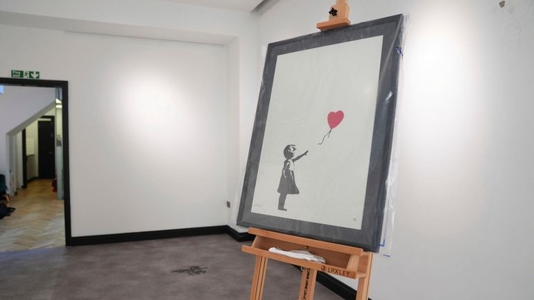 A Banksy painting, "Girl With Balloon," on display at the...