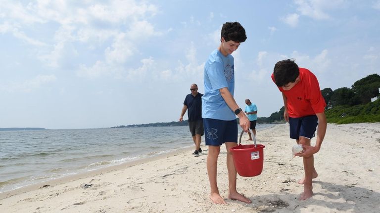 Tyler and Jacob Malkush, both 15, search for seashells at Peconic...