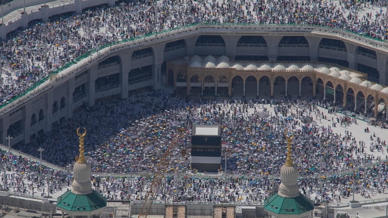 Muslim pilgrims circumambulate the Kaaba, the cubic building at the...