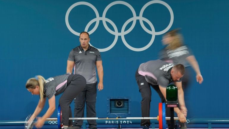 Loaders set the weight on the bar during the women's...