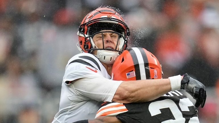 Cincinnati Bengals quarterback Joe Burrow, left, is hit by Cleveland...