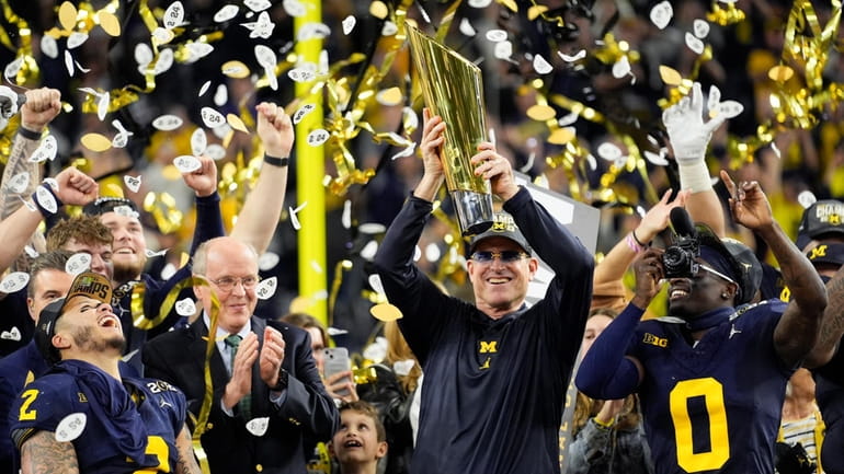 Michigan head coach Jim Harbaugh celebrates with the trophy after...