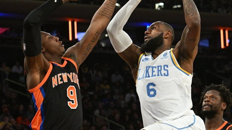 Lakers forward LeBron James puts up a shot defended by Knicks...
