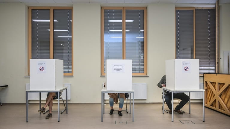 Voters sit behind polling booths at a polling station set...