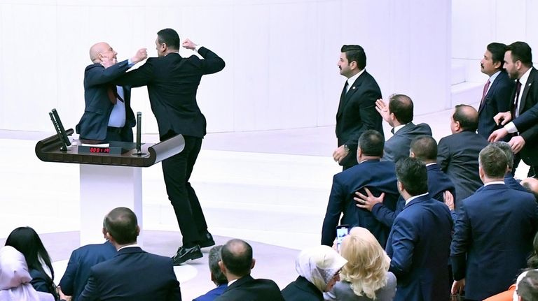 Turkey's AK Party lawmaker Alpay Ozalan, second left, scuffles with...